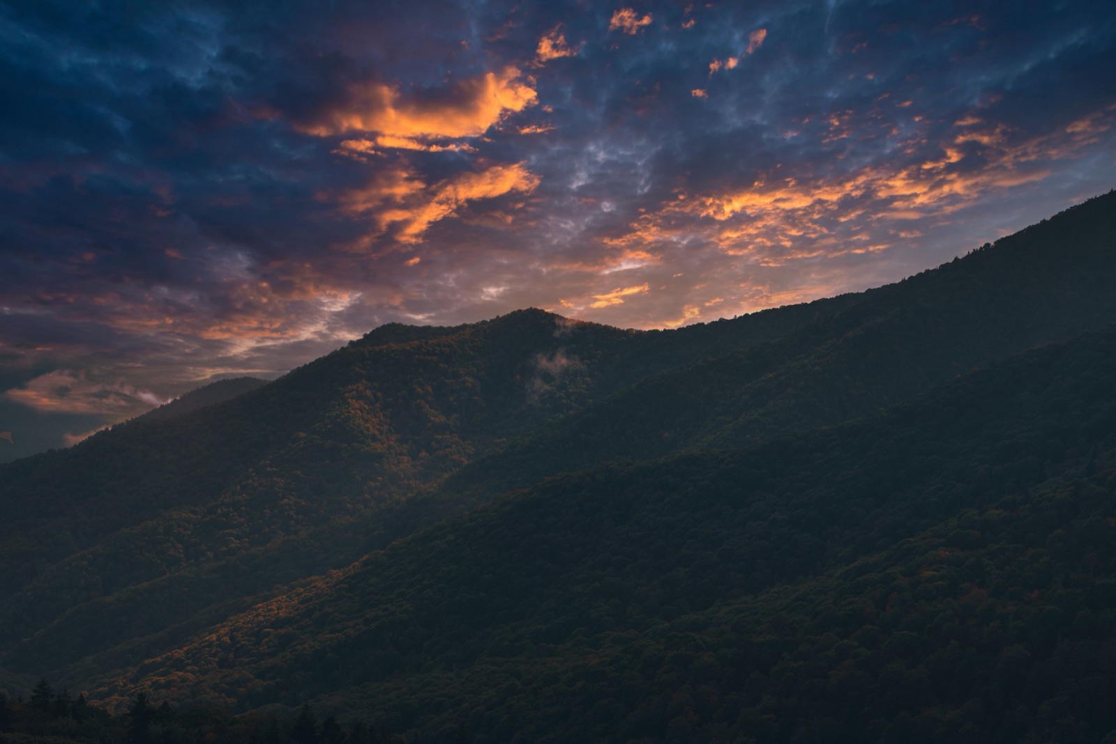Golden-hour light burning across layered Smoky Mountain ridgelines at sunset